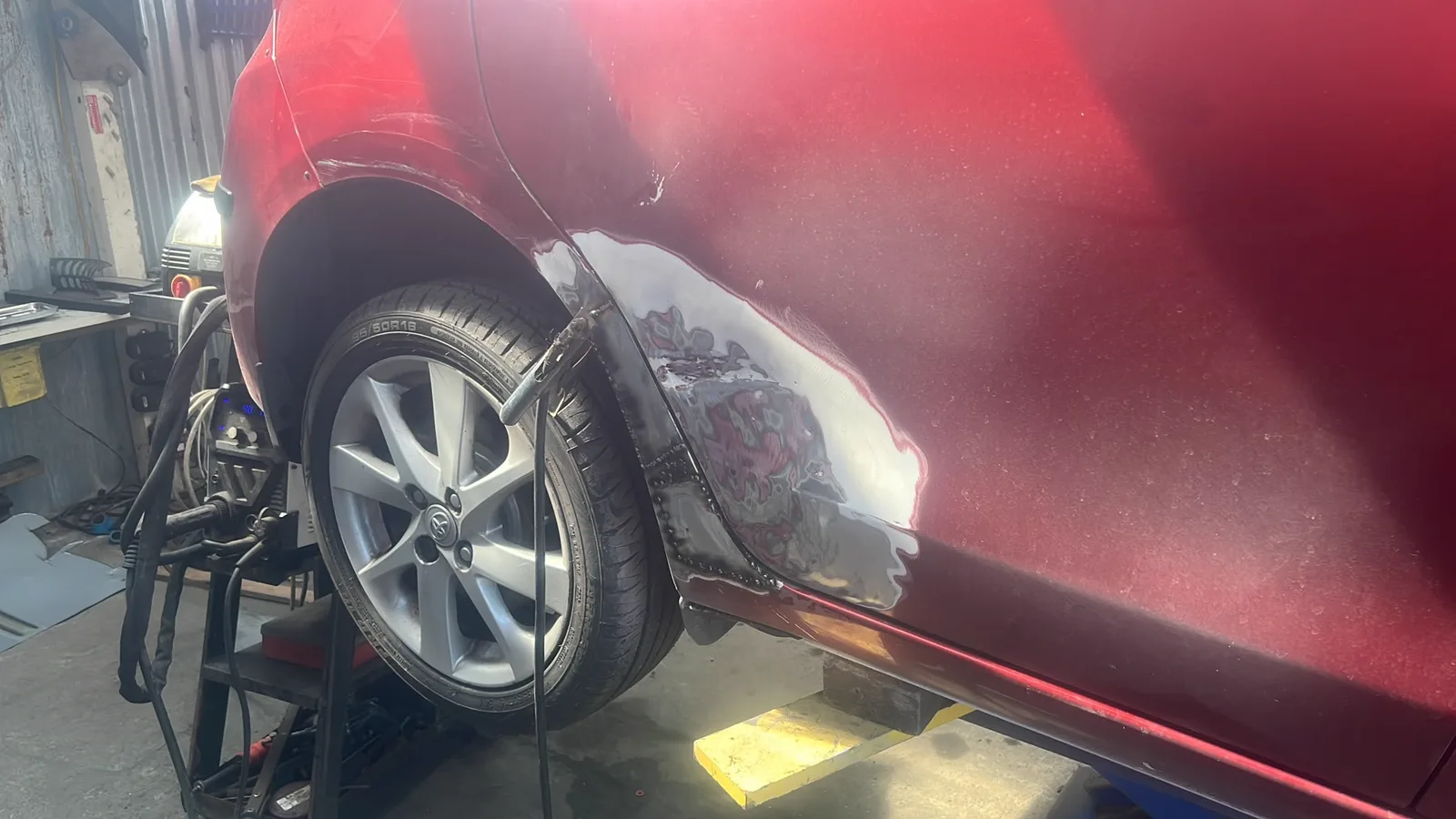 Rear quarter panel of a red car stripped back and prepared for repair
